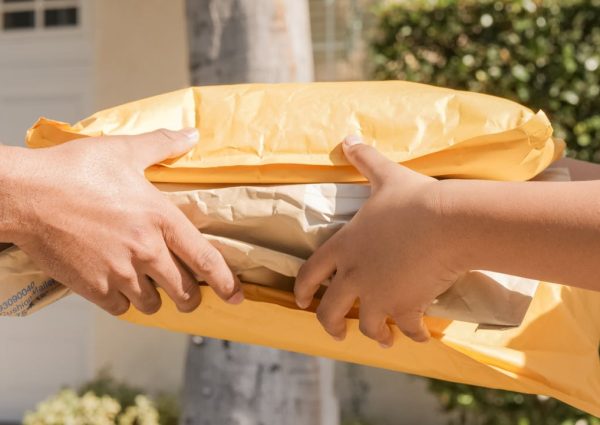 pexels-photo-6994138 Close-up of two hands exchanging packages, symbolizing delivery and communication.